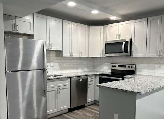 Renovated kitchen with stainless steel appliances and upgraded cabinets, flooring, and  counter tops at Stuart Woods* Apartments, Herndon, 20170
