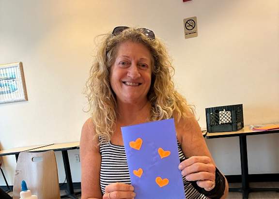 A woman is holding a paper with cut-out hearts.