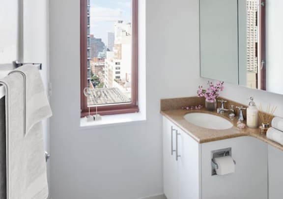 A bathroom with a large window overlooking a cityscape at The Ellington Apartments, New York, NY, 10019