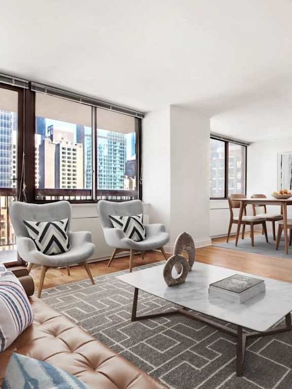 A living room with a large window and a view of the city at The Ellington Apartments, New York, NY, 10019