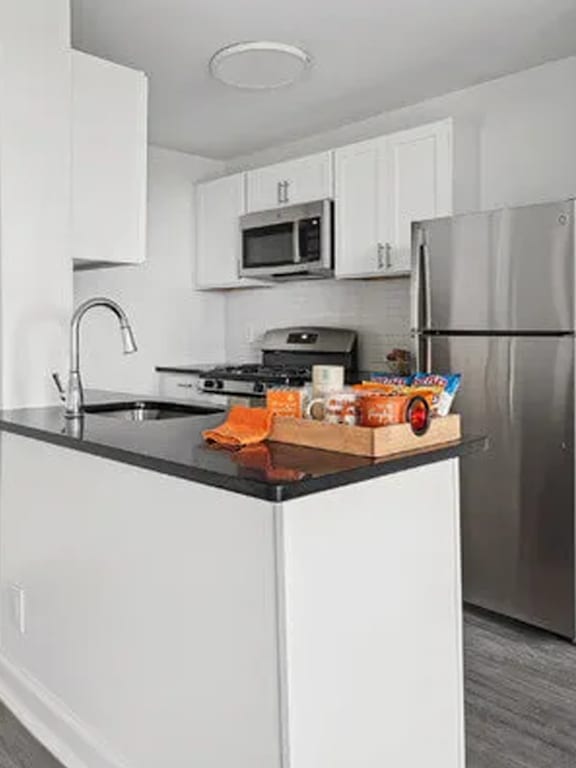 A kitchen with a black counter top and white cabinets.