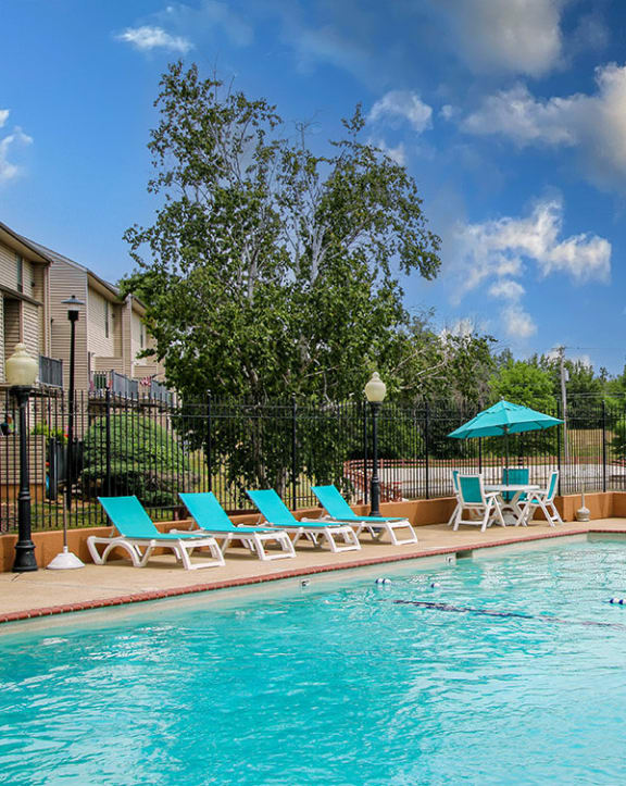 a swimming pool with chaise lounge chairs and an umbrella