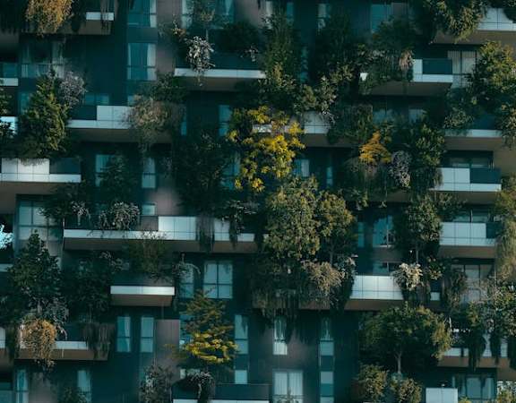 a picture of an apartment building with green plants on the balconies
