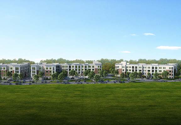 A large grassy field with a row of buildings in the distance.