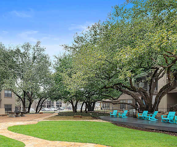a park with grass and trees and a patio with blue chairs at Waters Edge Apartment Homes, Georgetown, TX, 78626