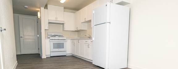 A kitchen with white appliances and wooden floors.