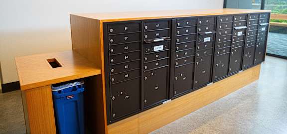 a lockers in a classroom with a blue trash can