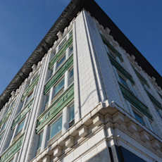 A tall building with a green awning is seen from below.