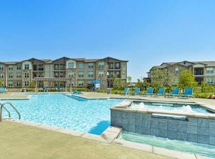 a swimming pool with blue chairs and an apartment building in the background