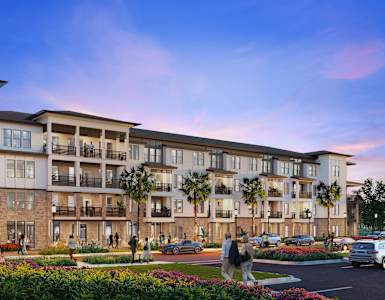 A large apartment complex with multiple balconies and a parking lot in front.