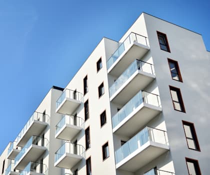 A tall white building with balconies on each floor.