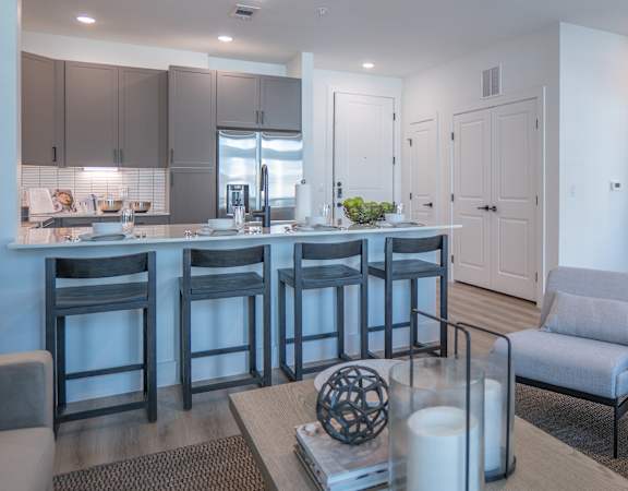 A modern kitchen with a bar area and a living room area.