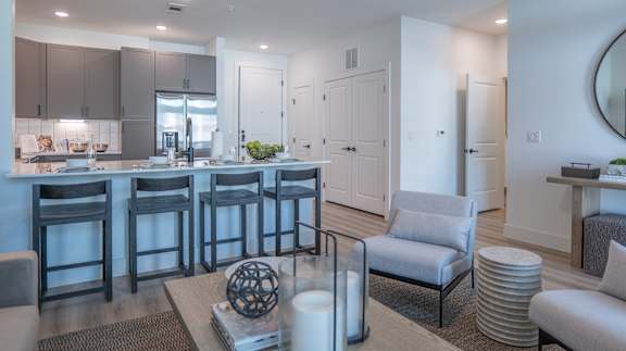 A modern kitchen with a bar area and a living room area.