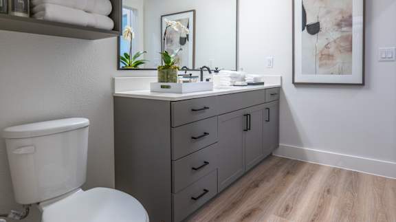 A bathroom with a toilet, sink, and mirror.