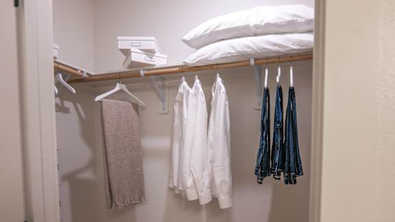 A white shirt is hanging on a hanger in a closet.