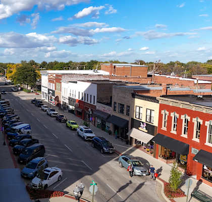 A street view of a town with cars parked on the side of the road.