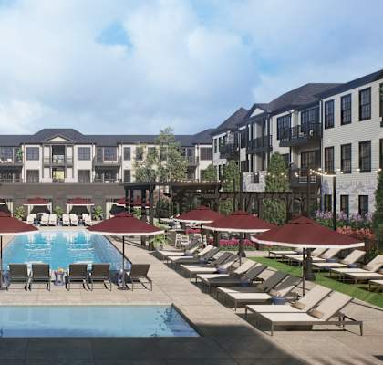 A large swimming pool surrounded by lounge chairs and umbrellas in front of apartment buildings.