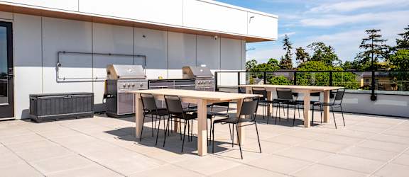 A patio with a table and chairs is set up outside a white building.