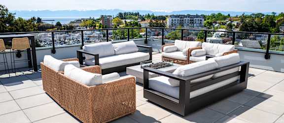Two white couches on a patio with a view of the water and mountains.