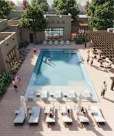 A pool area with people relaxing and sunbathing.