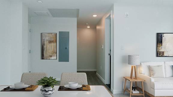 A modern dining room with a white couch, a wooden table, and two chairs.