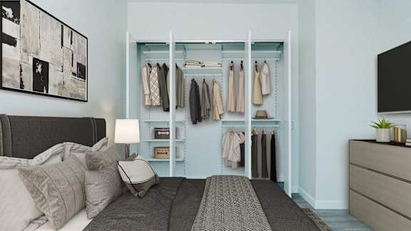 A bedroom with a bed, a nightstand, a wall-mounted closet, and a painting on the wall.