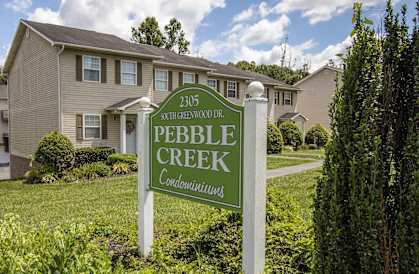 a sign for the pebble creek neighbourhood in front of a house