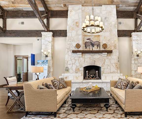 a living room with couches and a table and a fireplace at Lakeline East Apartments, Cedar Park