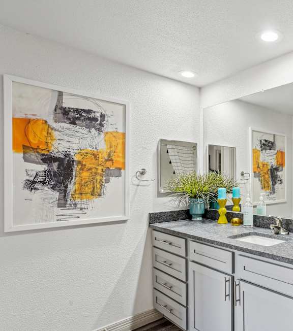 A bathroom with a white toilet and a sink with a cabinet underneath it.