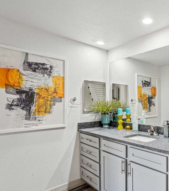 A bathroom with a white toilet and a sink with a cabinet underneath it.