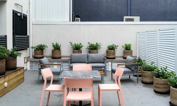 a patio with tables and chairs and potted plants