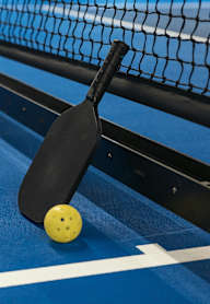 A paddle ball game is set up on a blue court.