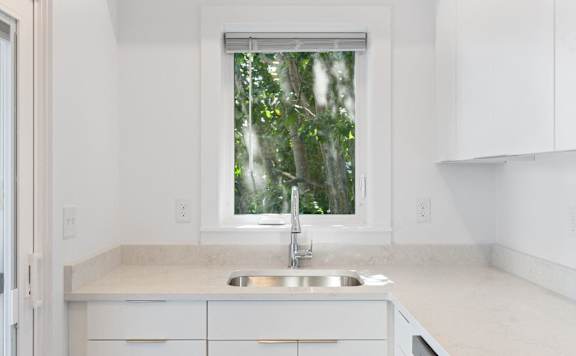 A modern kitchen with a refrigerator, oven, and a view of the outdoors through the door.