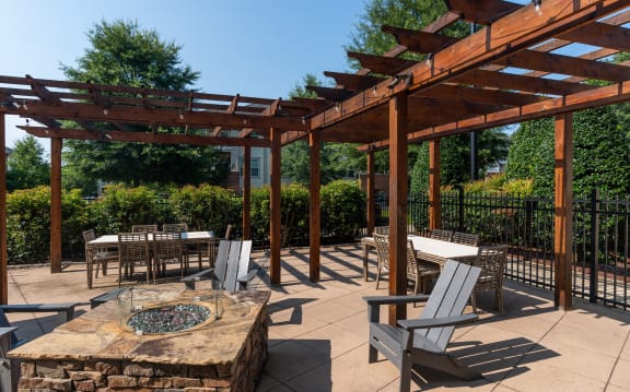 a patio with a table and chairs under a wooden pergola