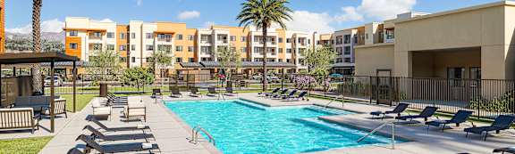 Pool area with sun loungers and palm trees at Vivir at Ballpark Village Apartments, Goodyear, AZ 85338