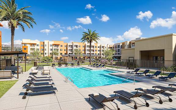 Pool area with sun loungers and palm trees at Vivir at Ballpark Village Apartments, Goodyear