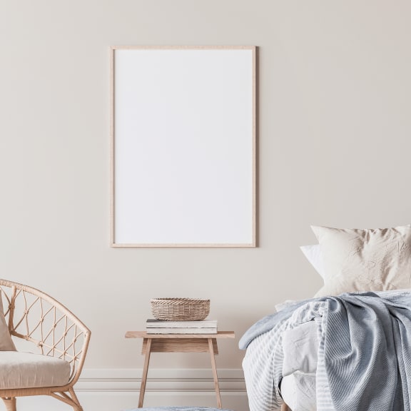 a bedroom with a bed and an empty picture frame on the wall