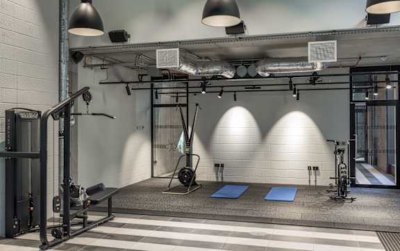 A gym with a variety of equipment including a squat rack, bench, and weights at Beton Apartments, Wembley, HA9 0SL