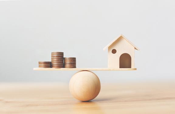 a balancing egg and coins on a shelf with a house