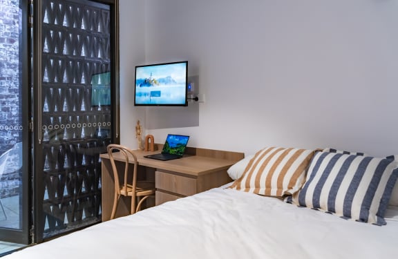 a bedroom with a bed and a desk and a television