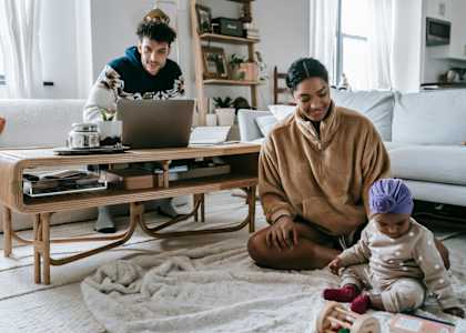 a family sitting on the floor in their living room looking at a laptop