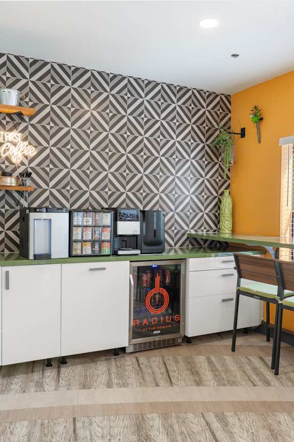 A kitchen with a white fridge and a white dishwasher with a black and white patterned wall behind it.
