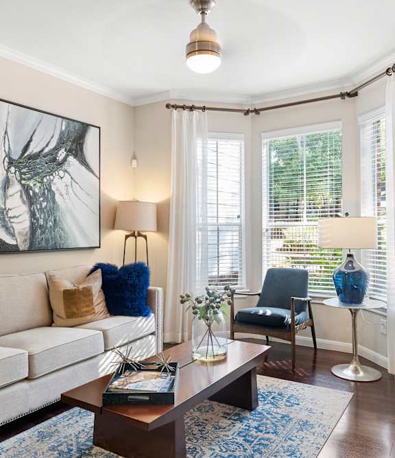 A living room with a large painting on the wall and a blue rug on the floor.