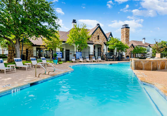 a swimming pool with chairs and a house in the background