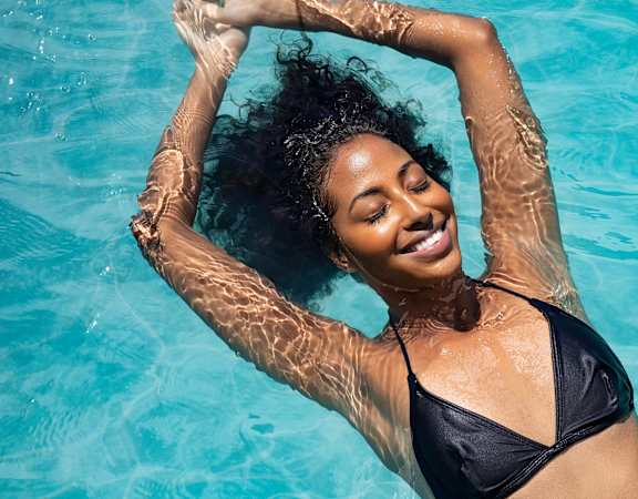 a woman laying in a pool with her hair in the water at Topaz Apartments, Los Angeles, 90013