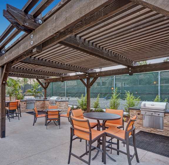 A patio with tables and chairs under a wooden pergola.