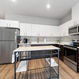 A modern kitchen with a stainless steel refrigerator and a black and white island.
