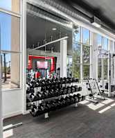A gym with a variety of equipment including weights and cardio machines.