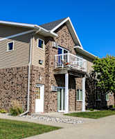 A brick apartment building with a white door and windows.