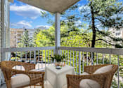 Thumbnail 8 of 25 - A balcony with a table and chairs overlooking a tree.